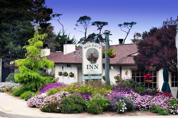 A building with a sign that reads "Deer Haven Inn Suites" and a flower garden in front.