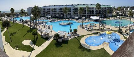 A hotel with multiple swimming pools, palm trees, and a large building in the background.