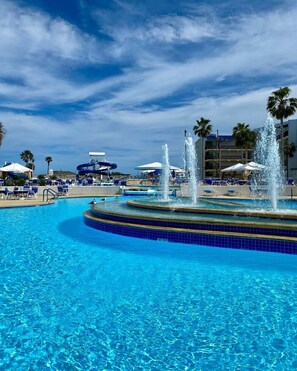 A swimming pool with a central fountain, surrounded by lounge chairs and umbrellas. - Port Royal Ocean Resort & Conference Center (Port Aransas)
