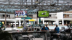 A spacious indoor area with multiple levels, featuring a bar area with seating and a pool in the background. - Port Royal Ocean Resort & Conference Center (Port Aransas)