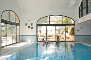 Una piscina cubierta, una piscina con cascada, tumbonas