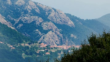 A mountainous landscape with a village nestled at its base, featuring traditional architecture and rocky terrain.