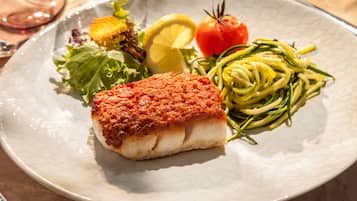 Um prato de comida com peixe, legumes e massa.