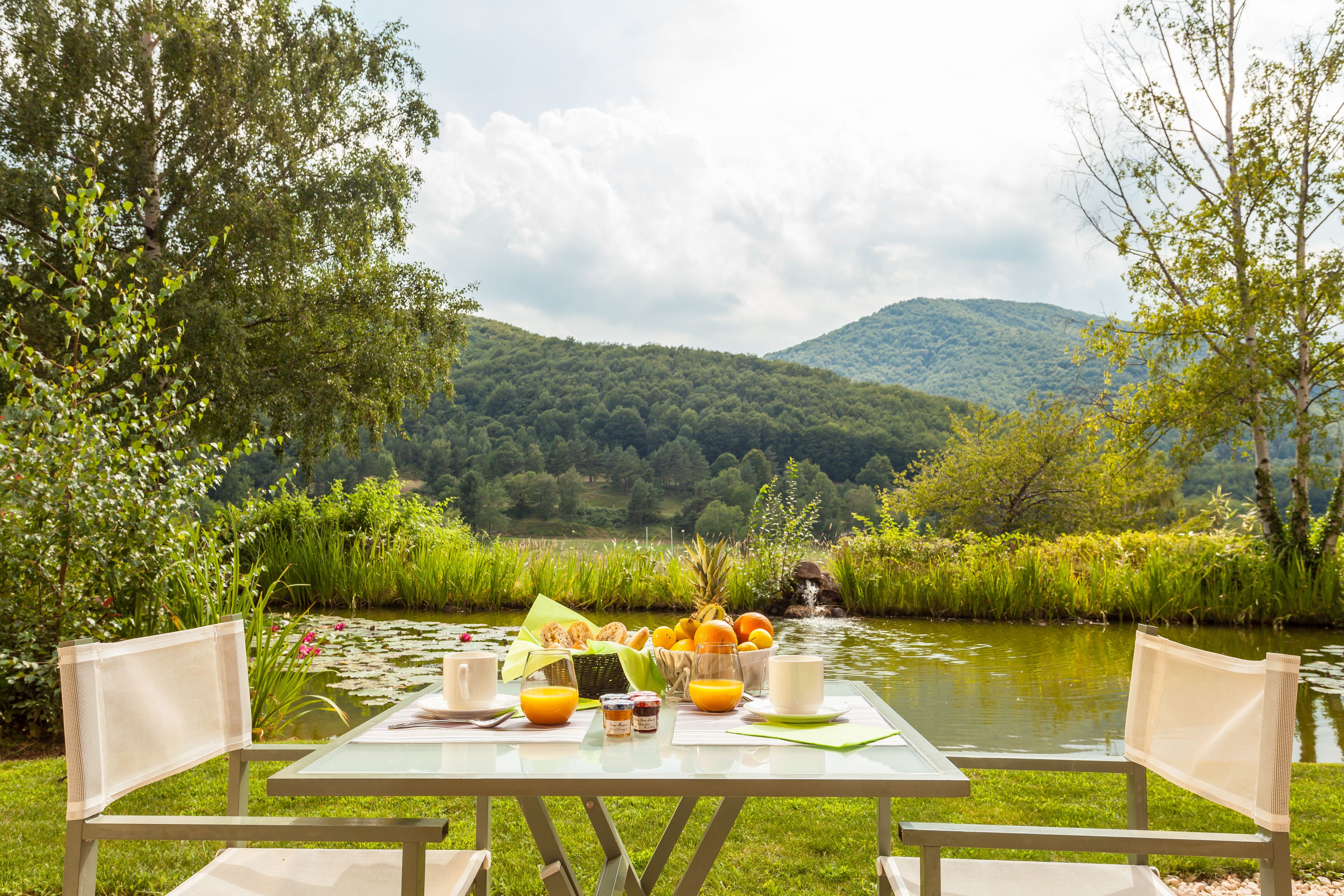 A table set for breakfast with a view of a lake and mountains.