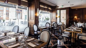 Et restaurantinteriør med flere spiseborde, stole og udsigt til gaden.