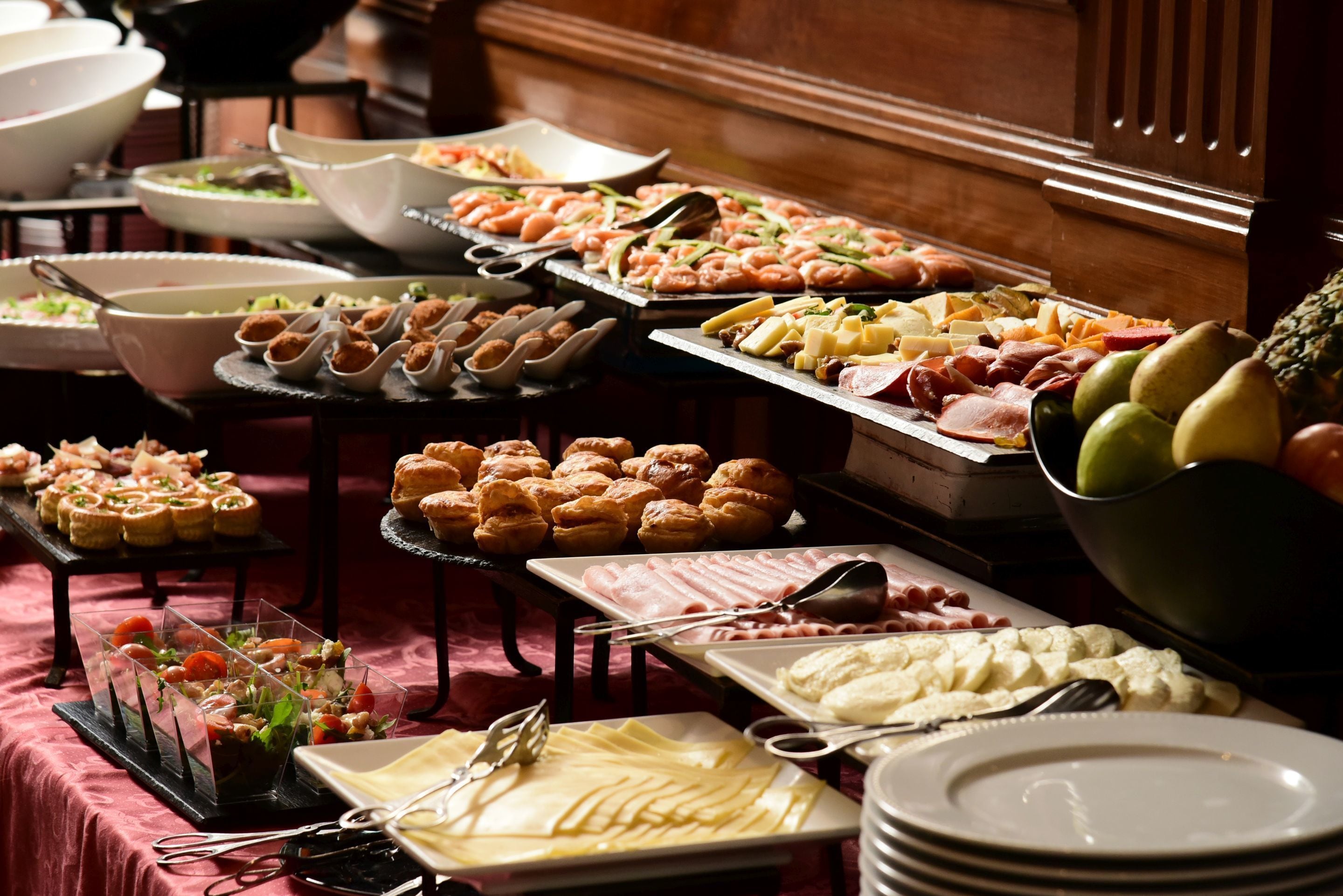 A buffet with various food items including pastries, meats, cheeses, and fruits.