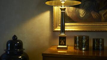 A lamp on a wooden table with a framed painting in the background.