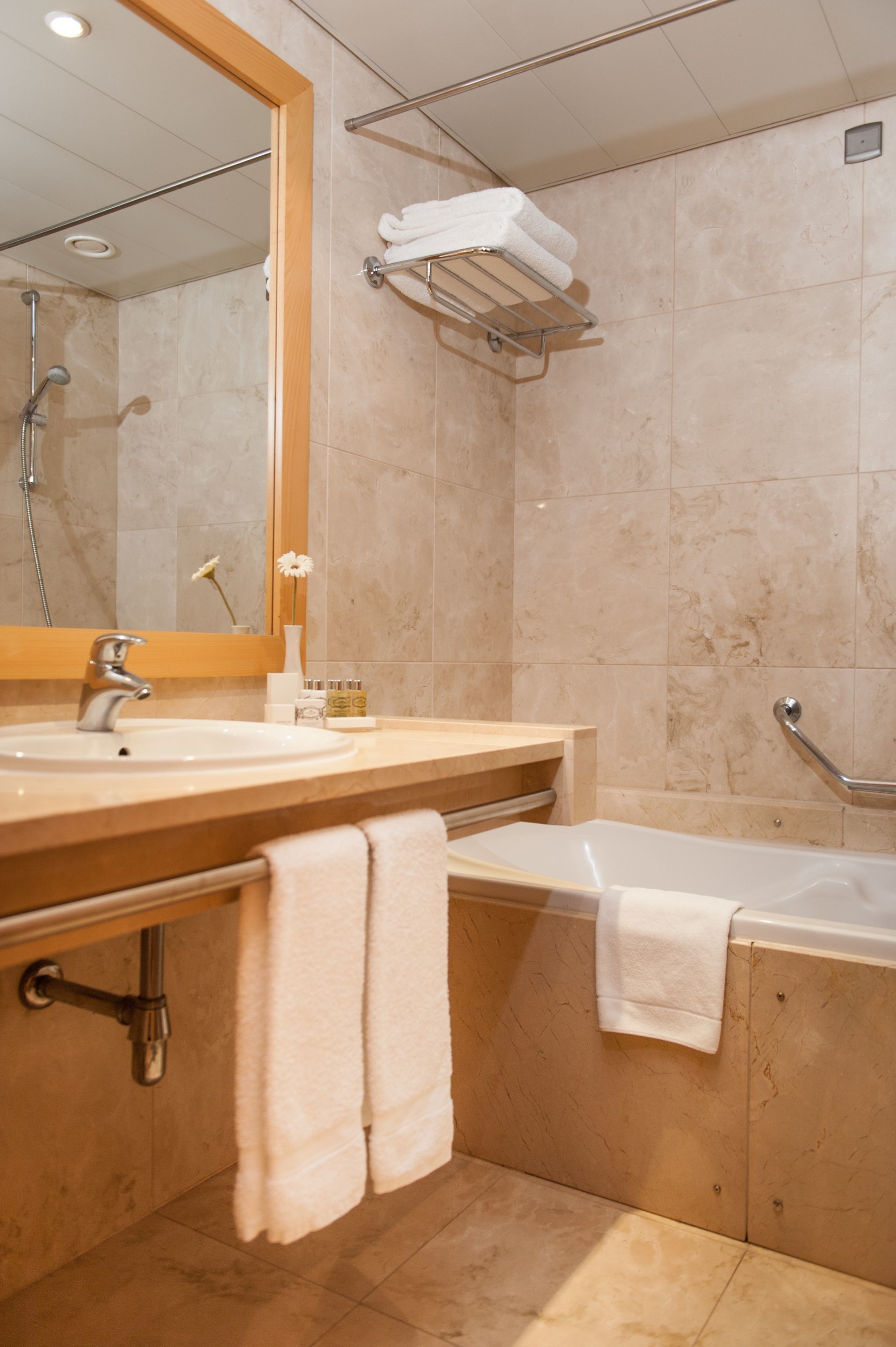 Un baño con lavamanos, espejo, ducha y bañera.