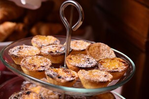A glass plate with several small pastries, possibly tarts, arranged on a stand.