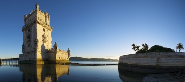 A historic tower by a calm body of water with a clear sky. - Hotel Real Palacio (Lisbon)