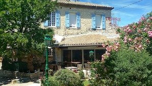 A stone building with blue shutters, outdoor seating, and a sign reading "L'Auberge de Tavel". - Auberge de Tavel (Tavel)
