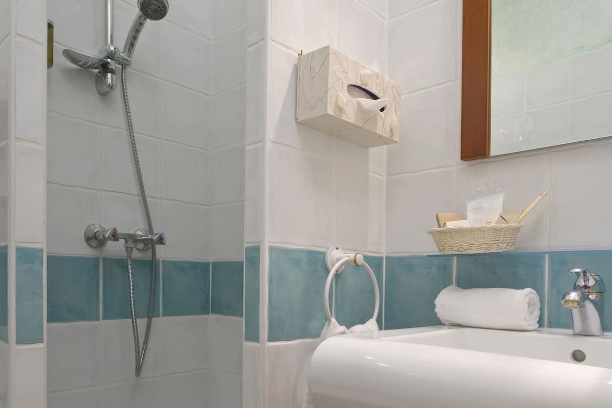 A bathroom with a shower, a sink, and a wooden cabinet.