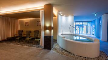 A spa area with a hot tub, seating area, and a view of the outdoors.
