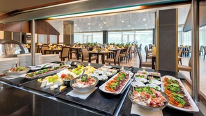 A buffet with various food items and a modern interior with tables and chairs. - Hunguest Szeged - ex Forrás (Szeged)