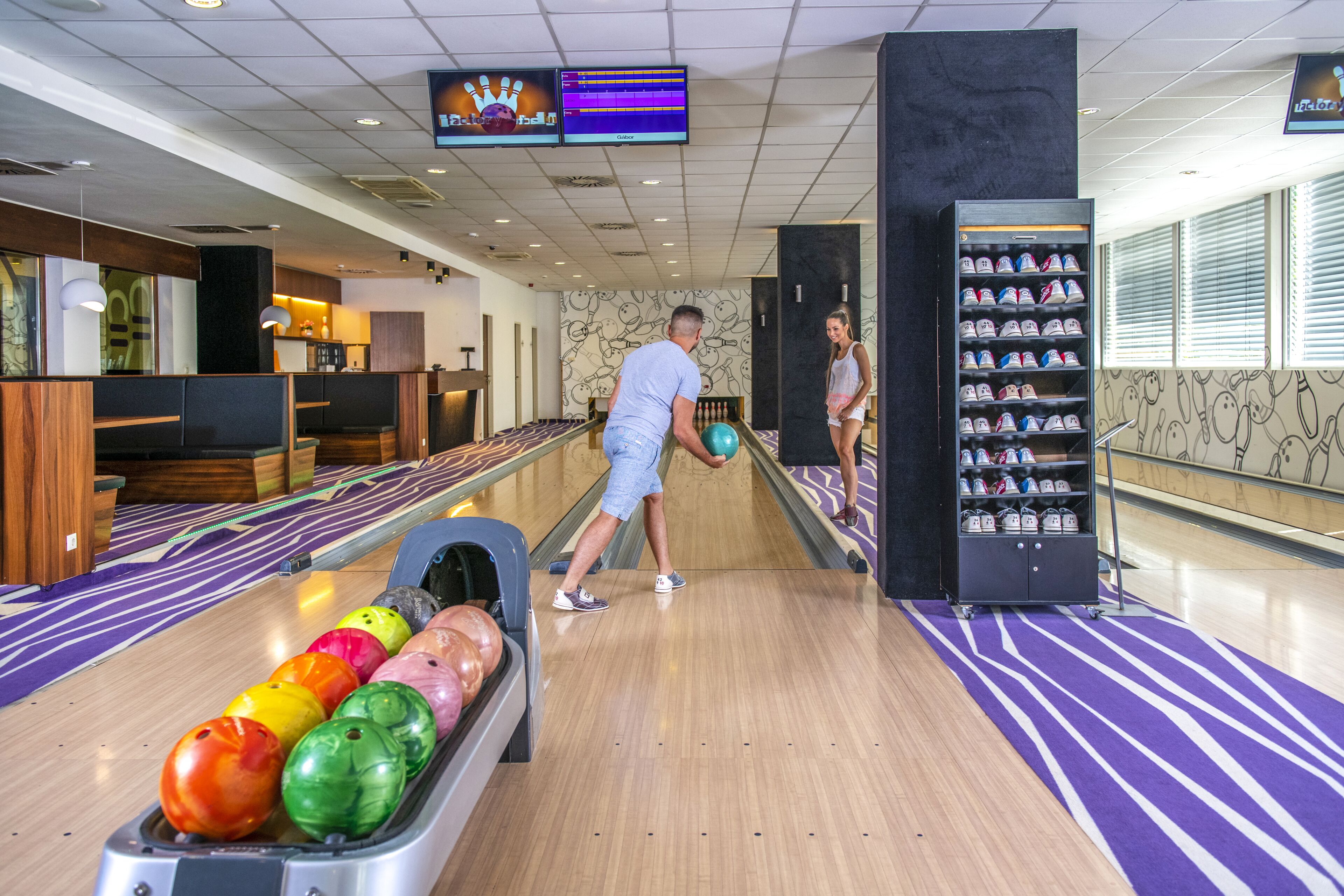 A bowling alley with multiple lanes, a shoe rental area, and a seating area with a counter.