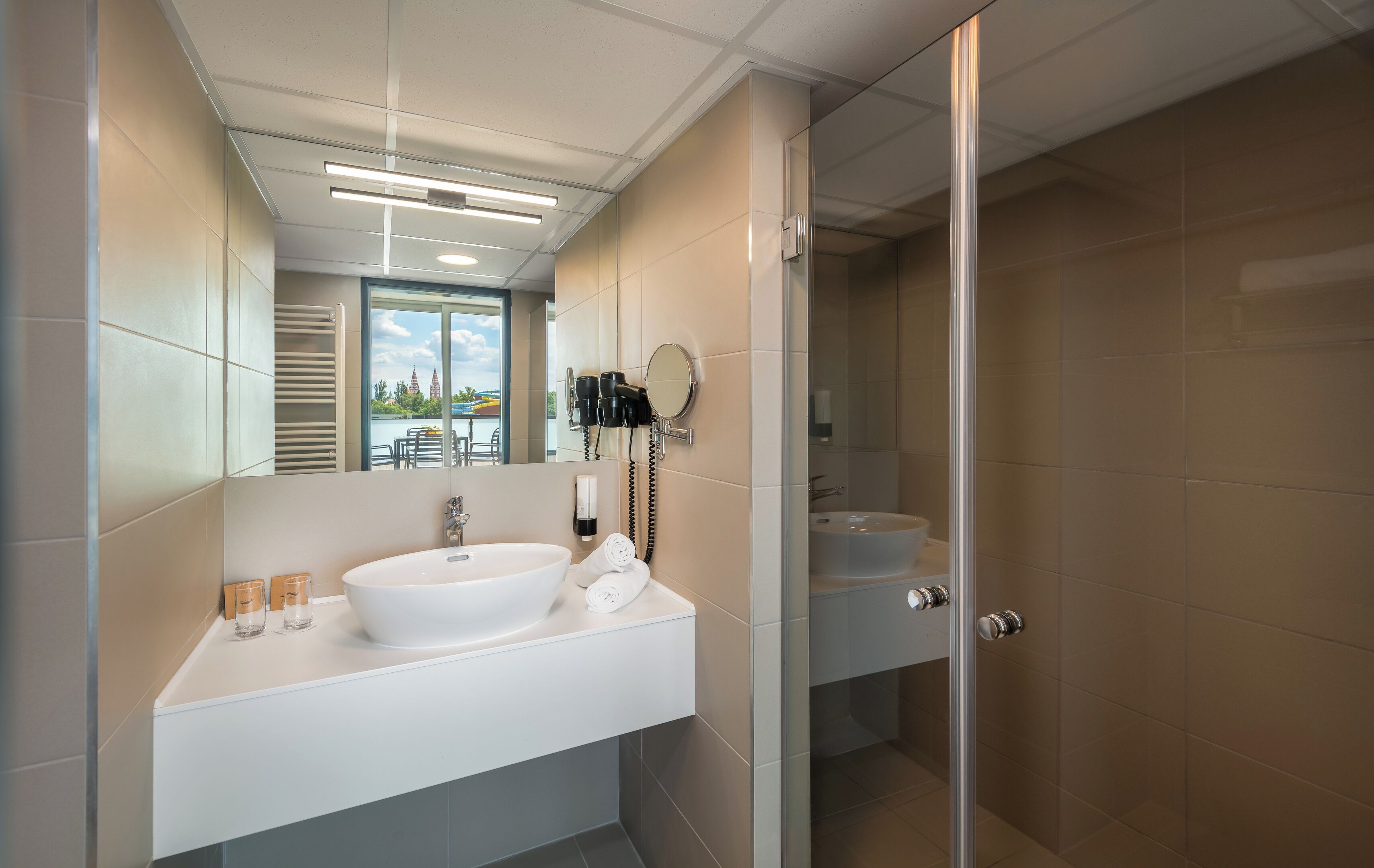 Een moderne badkamer met een groot wastafel, spiegel en een douchecabine van glas.