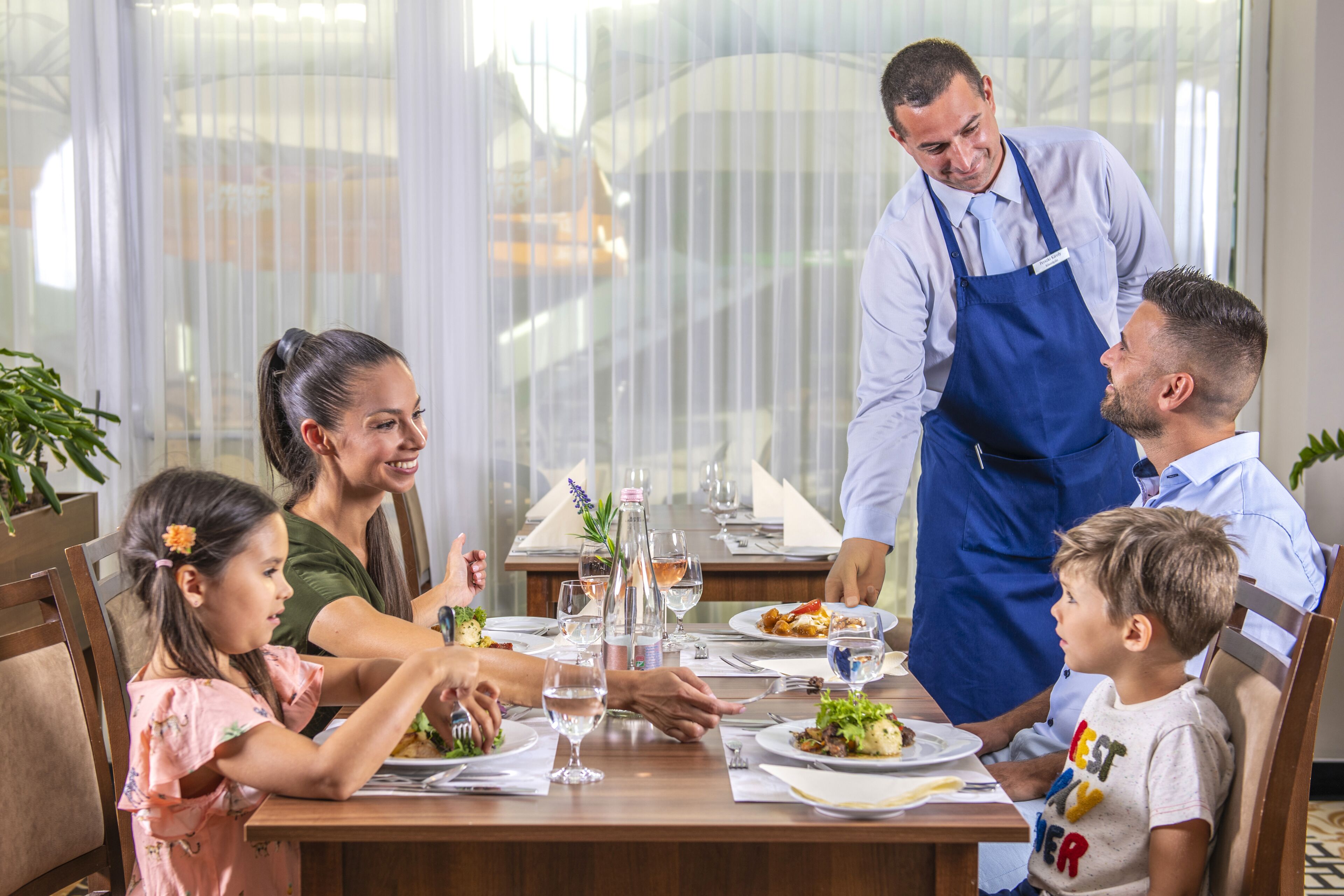 A family dining at a restaurant with a large window view.