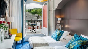 A hotel room with a bed, a desk, a chair, and a view of the outside. - Grand Hotel Gallia & Londres (Lourdes)