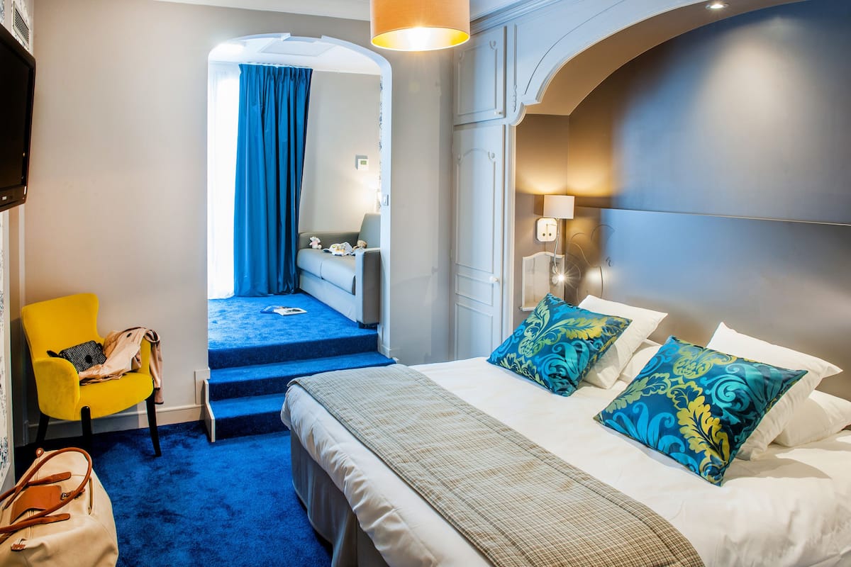 Ein Hotelzimmer mit Bett, Stuhl, Treppe und einem durch einen Bogen sichtbaren Badezimmer.