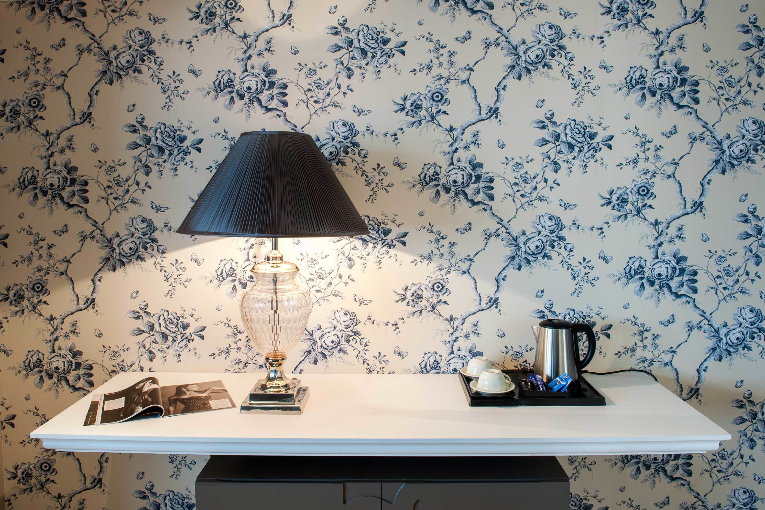 A table with a lamp, a kettle, and a tray with cups and a teapot.