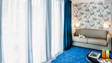 A room with a sofa, a coffee table with a tablet and juice bottles, and a patterned wall.