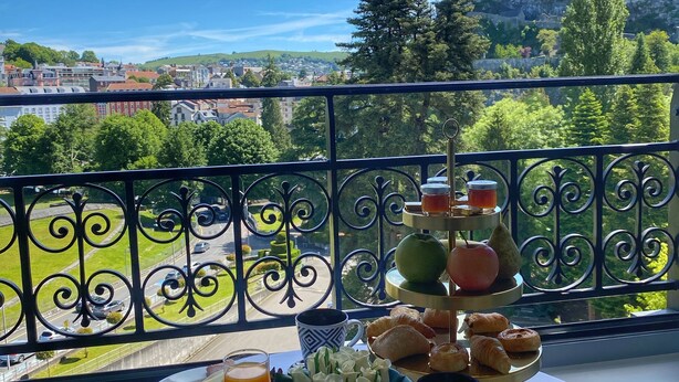 A breakfast table with various dishes and a scenic view of a town and castle. - Grand Hotel Gallia & Londres (Lourdes)