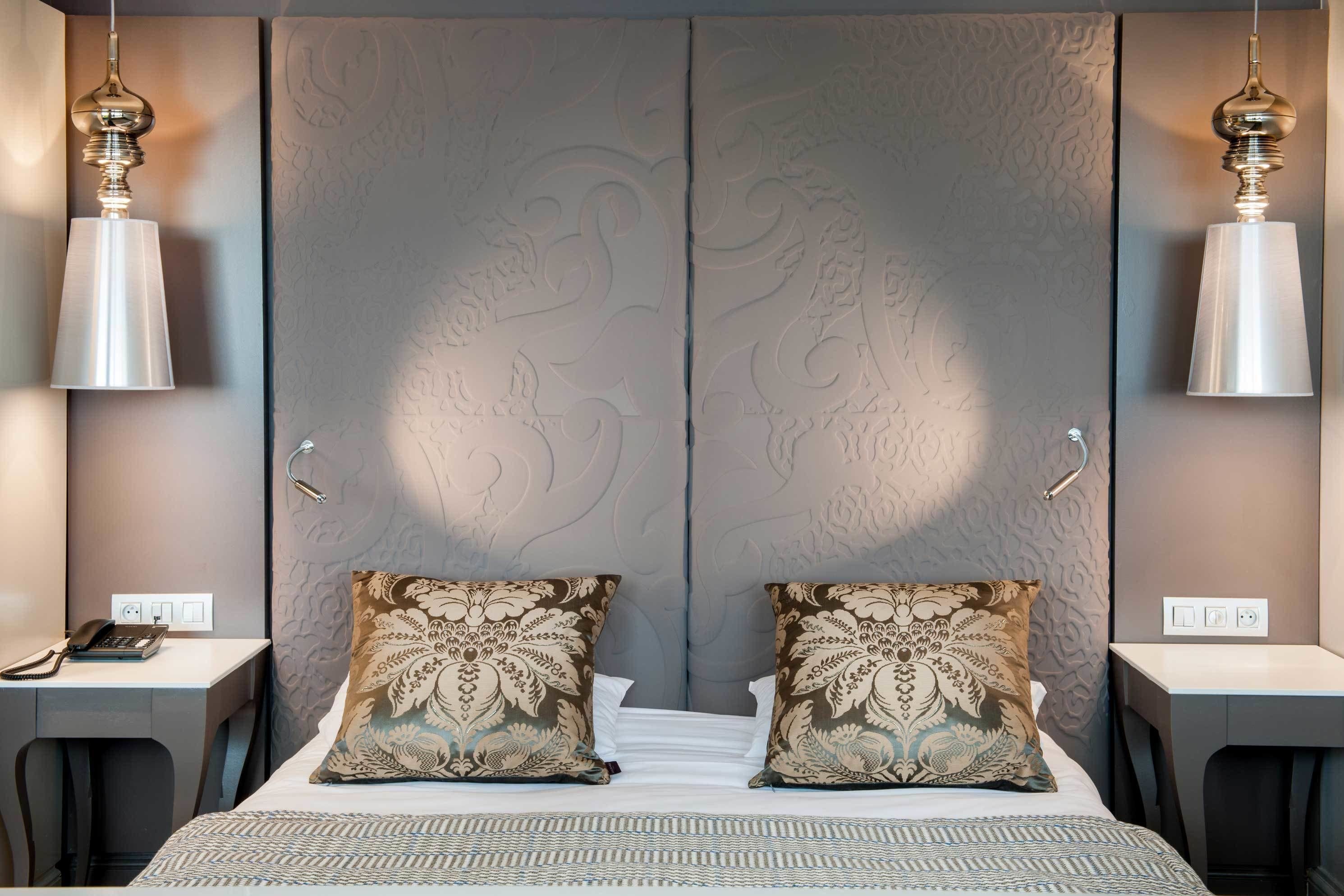 A hotel room with a large bed, two bedside tables, a desk, and a telephone.