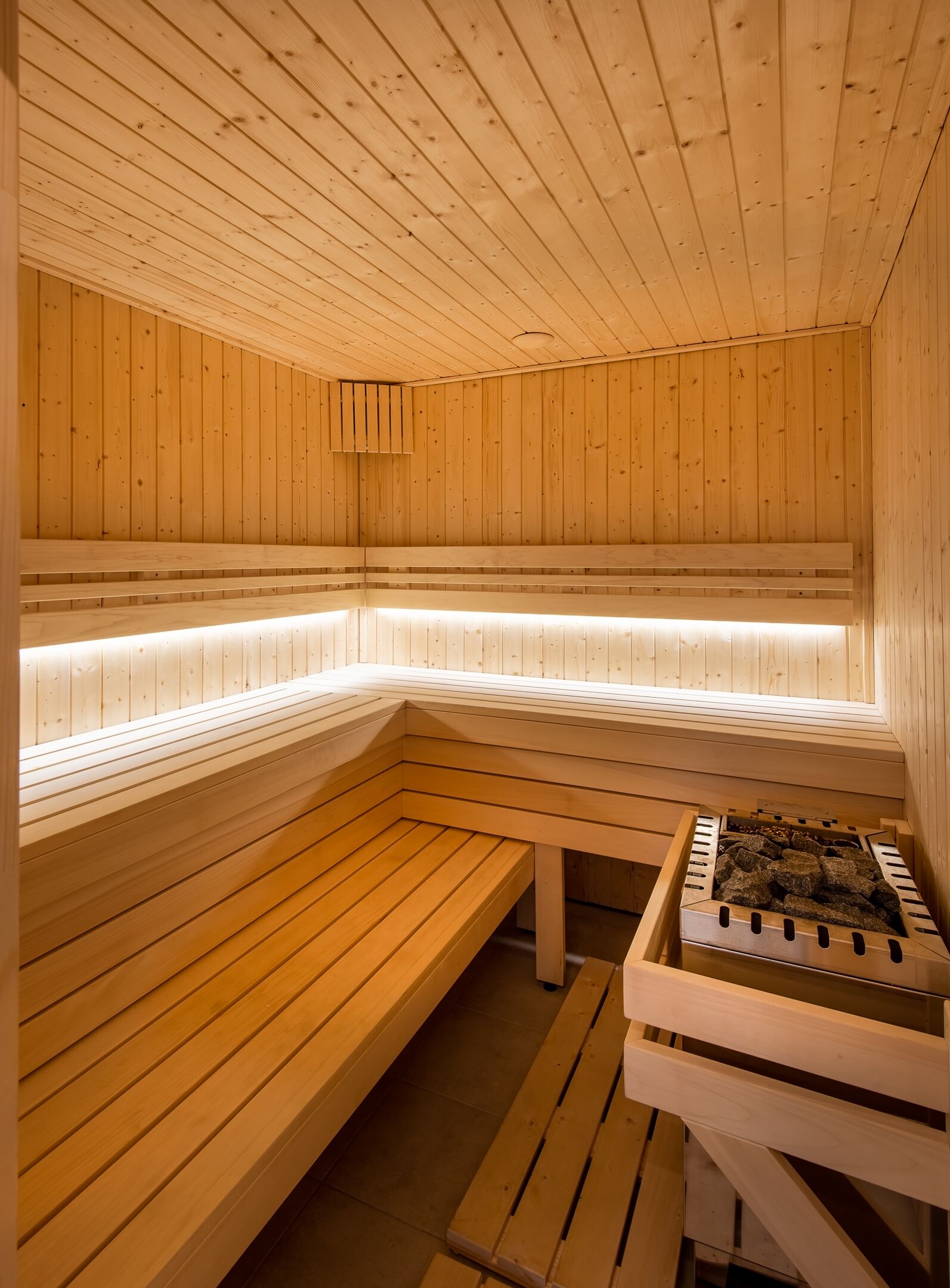 Uma sauna de madeira com bancos e um elemento de aquecimento em pedra.