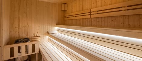 Una sauna con bancos de madera y una pileta de piedra.