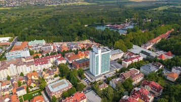 An aerial view of a town with a mix of residential and commercial buildings, including a prominent hotel with a modern design and a large parking area.