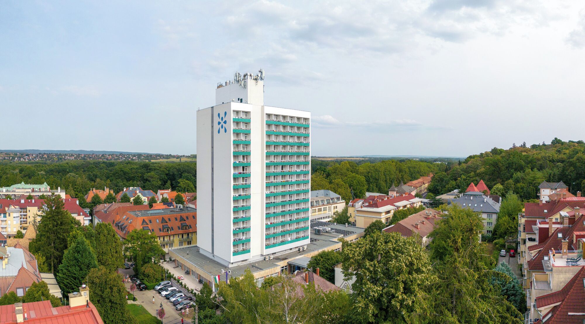 Un hotel alt amb nombrosos pisos, envoltat d'edificis residencials i vegetació.