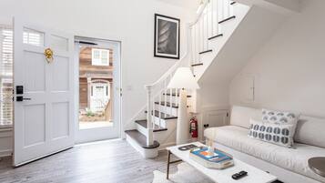 A modern living room with a white sofa, a coffee table, and a staircase leading to an upper level.