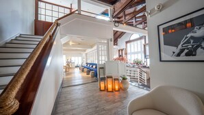 A spacious interior with a wooden staircase, a blue sofa, and a white chair. - EHP Resort & Marina (East Hampton)