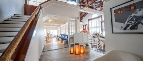 A spacious interior with a wooden staircase, a blue sofa, and a white chair.