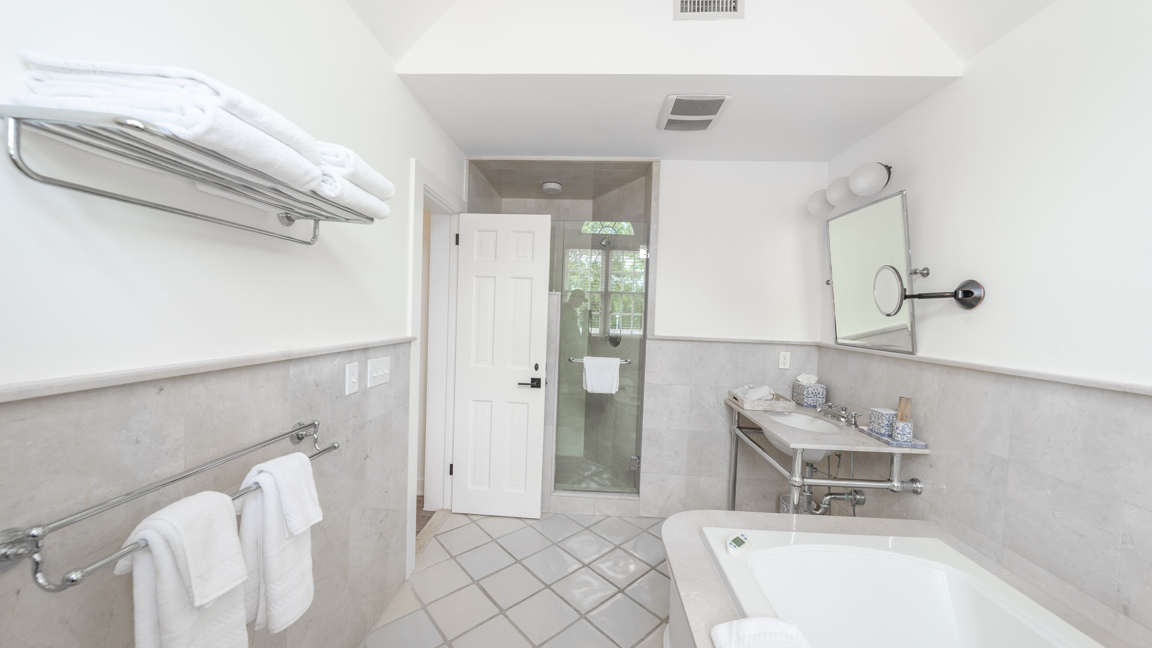 Uma casa de banho moderna com banheira, chuveiro, toucador com espelho e porta-toalhas.