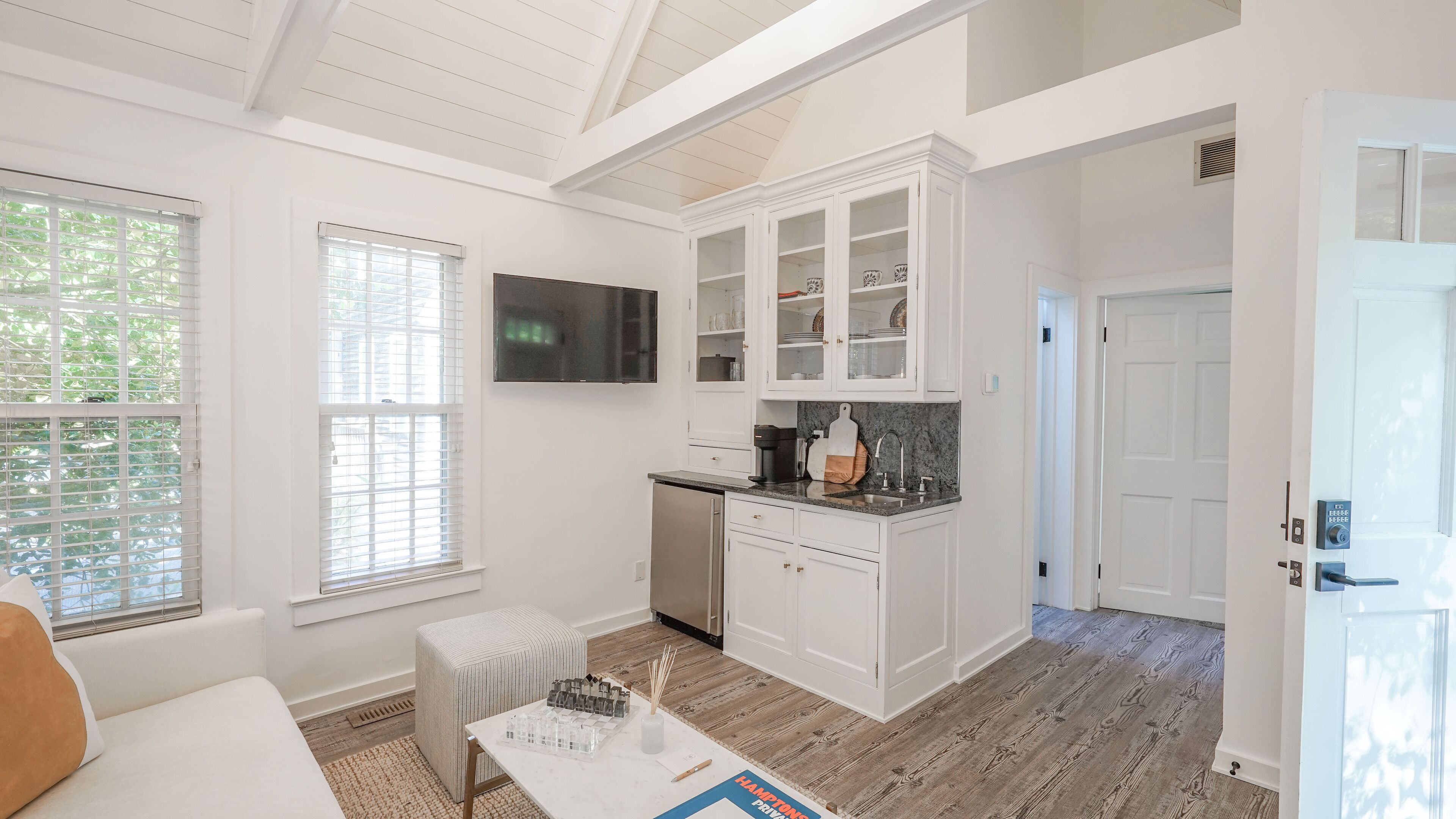 A modern kitchen with white cabinetry, a built-in oven, and a countertop with a coffee maker.