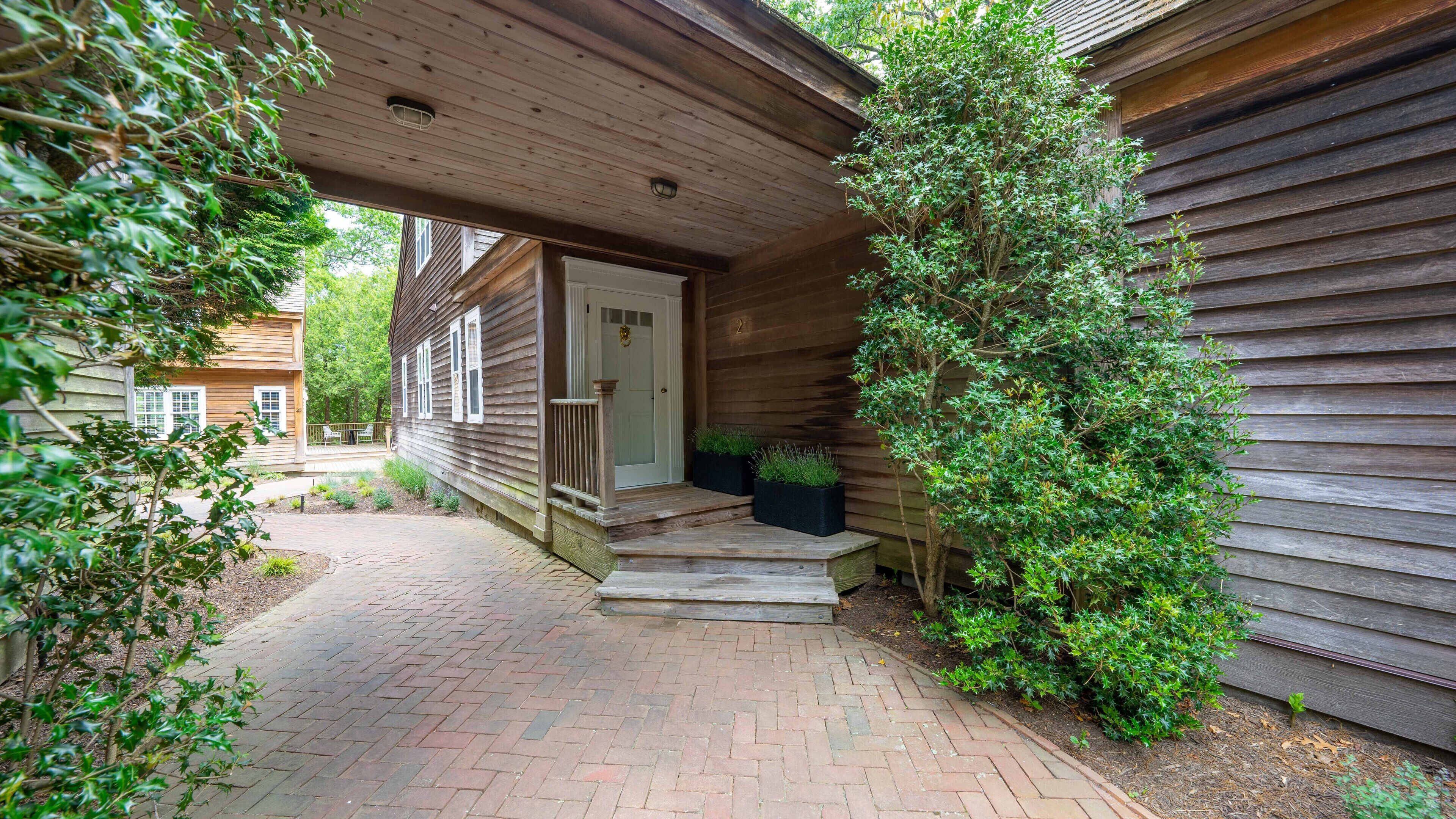 A wooden house with a brick pathway leading to the front door.