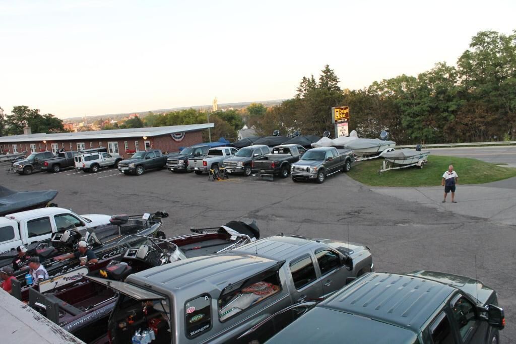 A parking lot with several vehicles, including trucks and boats, and a building in the background.