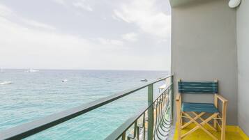 A balcony with a view of the sea, a chair, and a railing.