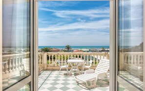 Ein Balkon mit kariertem Boden, weißen Stühlen und einem Tisch.