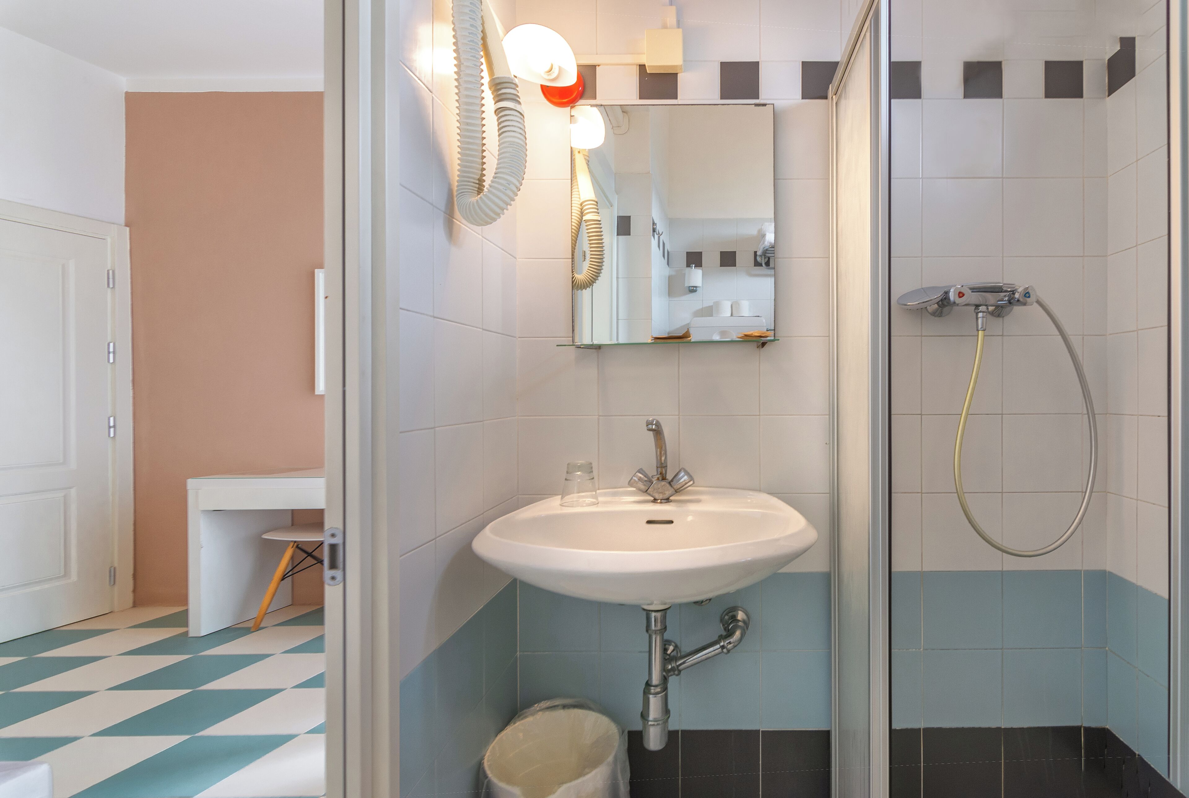 A bathroom with a white sink, a mirror, and a shower.