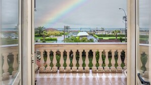 An open balcony with a view of a garden, a building, and a rainbow. - Happy Hotel (Pietrasanta)