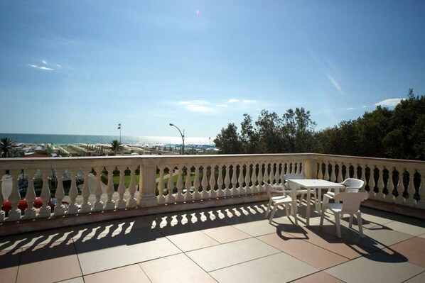 A balcony with a view of the sea, featuring a table and chairs. - Happy Hotel (Pietrasanta)