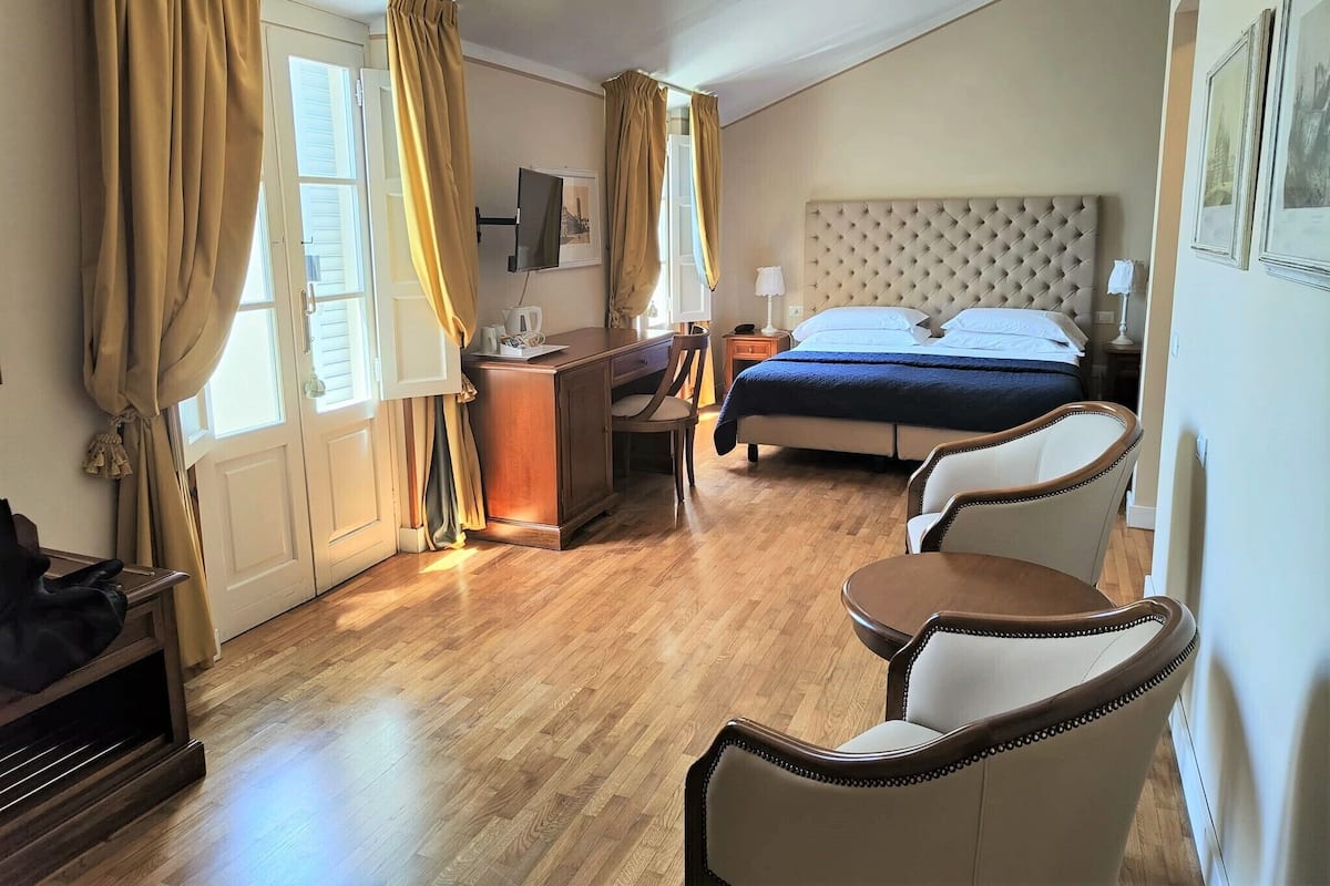 A hotel room with a bed, a desk, a chair, and a small table.