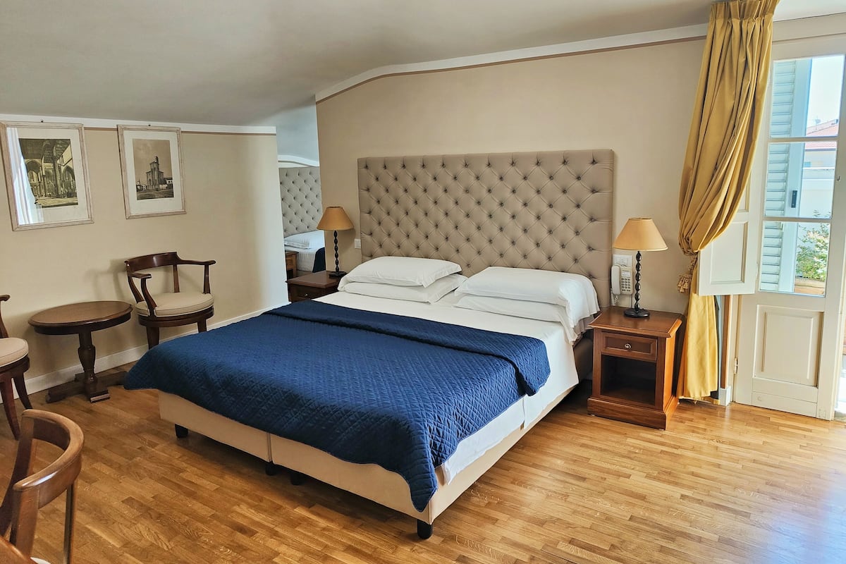 A bedroom with a large bed, two bedside tables, a chair, and a small table.