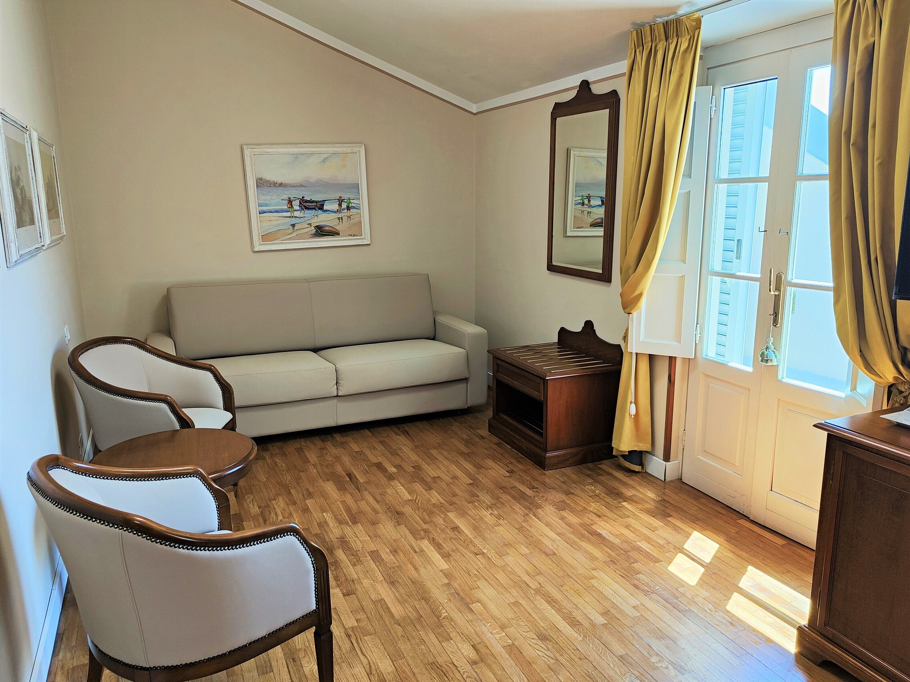 A room with a sofa, a chair, a wooden cabinet, a mirror, and a painting on the wall.
