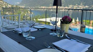 A table set for dining with a view of mountains and a pool.