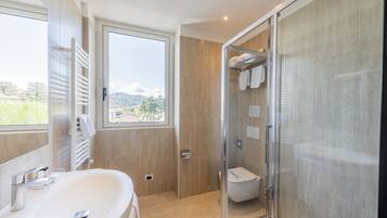 A modern bathroom with a large window, a glass shower enclosure, and a white sink.