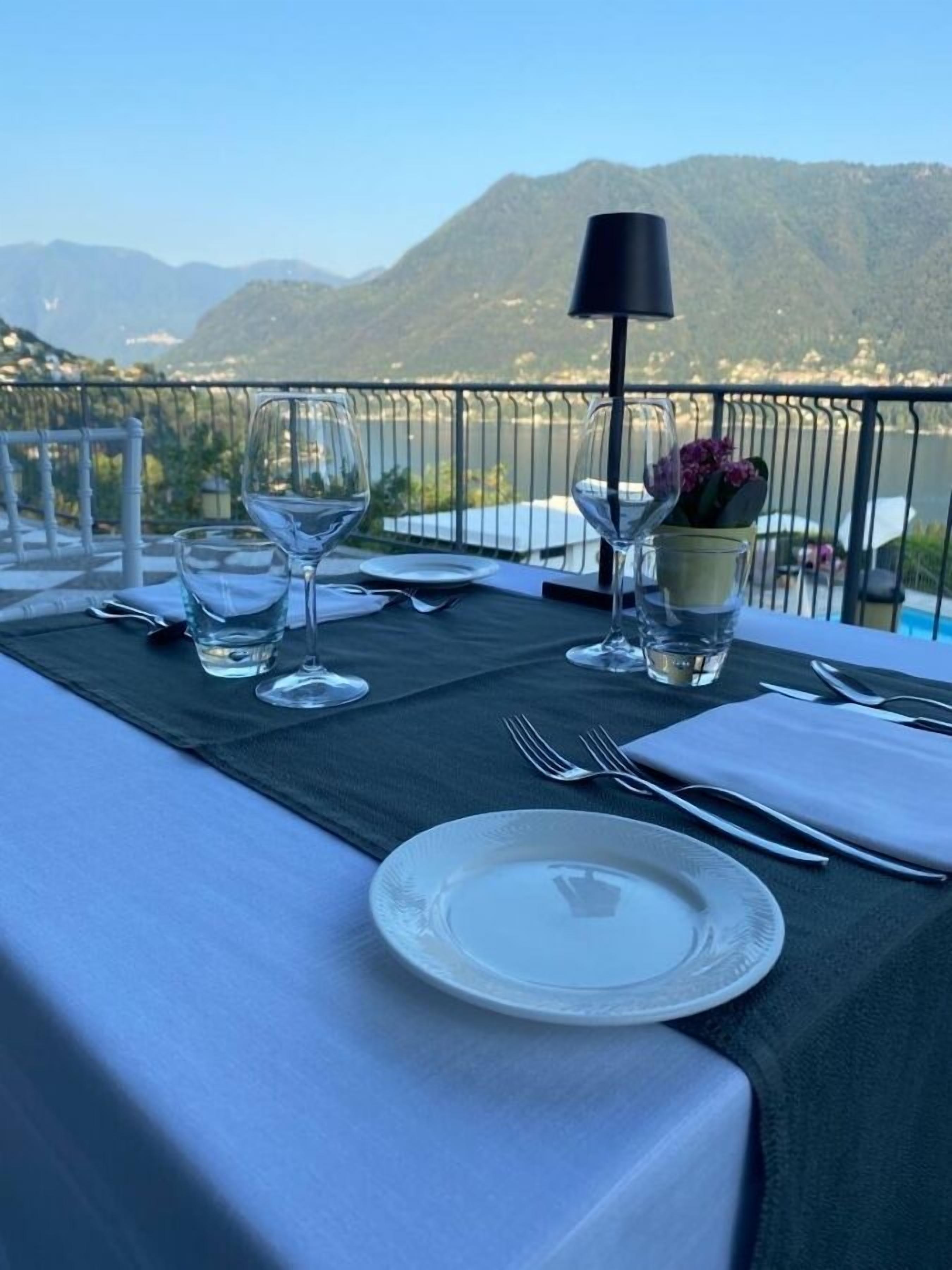 Une table dressée pour le dîner, avec vue sur les montagnes et un plan d’eau.