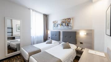 Ein Hotelzimmer mit zwei Betten, einem großen Spiegel, einem Bild und einem Nachttisch mit Telefon.